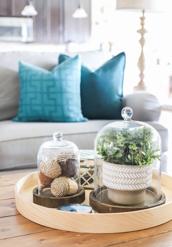 a round tray with acorns in a cloche and potted greenery in a cloche for a stylish and modern feel in the space