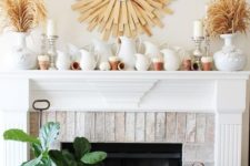 a rustic fall mantel with a sunurst decoration, dried herbs in vases, lots of jugs and tiny white pumpkins
