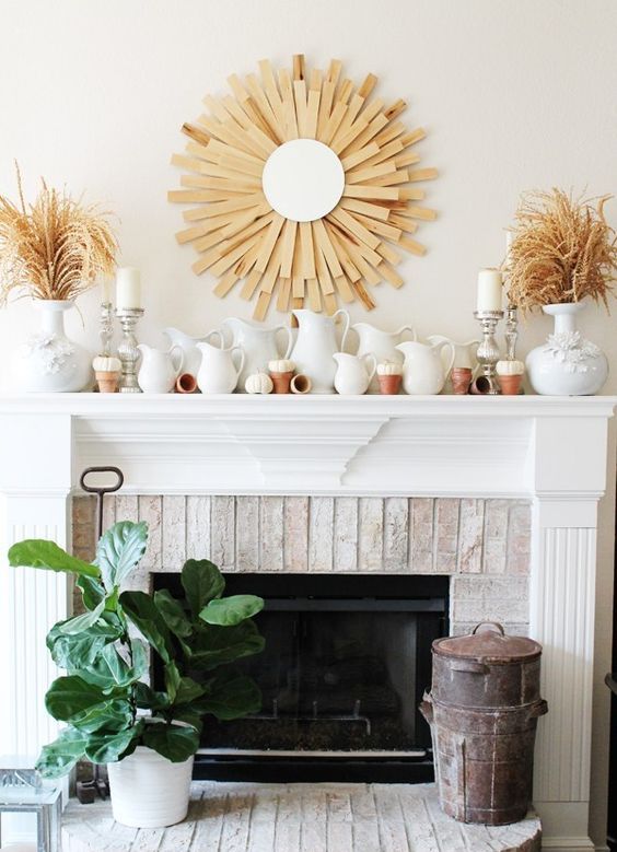 a rustic fall mantel with a sunurst decoration, dried herbs in vases, lots of jugs and tiny white pumpkins