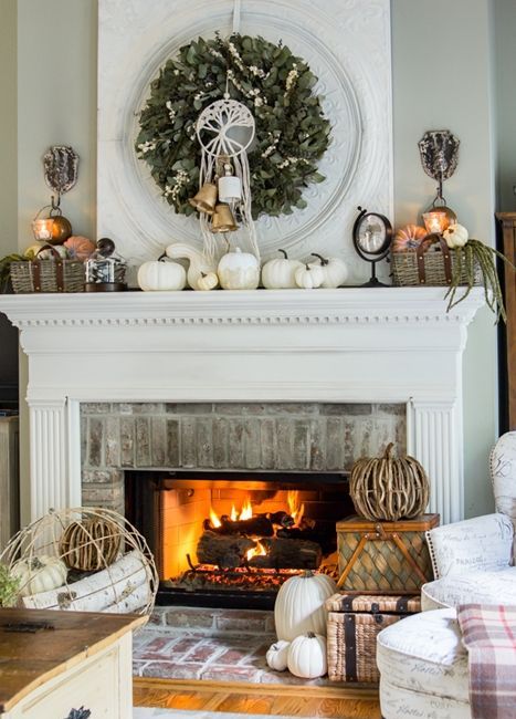 a rustic fall mantel with white pumpkins, baskets with faux pumpkins, a greenery wreath with bells and vine pumpkins