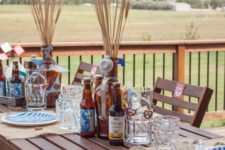 a simple outdoor fall tablescape done in beige and blue, with burlap placemats and wheat in bottles