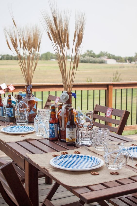 a simple outdoor fall tablescape done in beige and blue, with burlap placemats and wheat in bottles