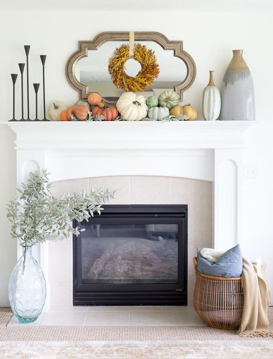 a stylish fall mantel with pastel pumpkins, a dried leaf wreath, vases and metal candleholders