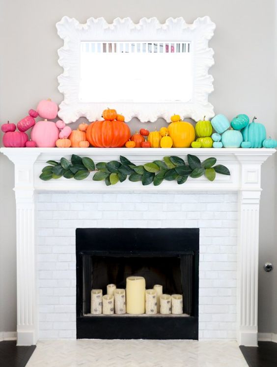 a super colorful fall mantel with super bright pumpkins and birch-inspried candles in the fireplace