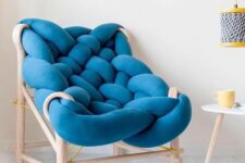 a super creative chair with a light-stained wooden frame and a piece of blue upholstery all bent and wrapped to form a seat and a back