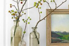 a trio of grey clear vases with branches and little apples on them