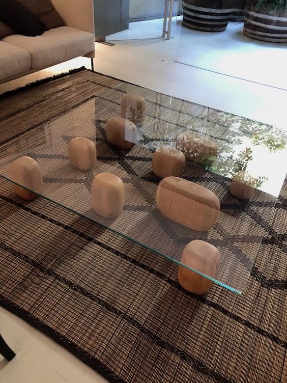 A unique coffee table of wooden pieces and a glass tabletop placed on them looks very zen like and creative