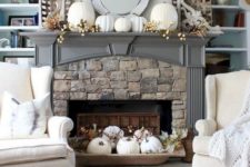 a vintage rustic mantel with fake berries, white pumpkins, a dough bowl with white pumpkins, leaves and berries