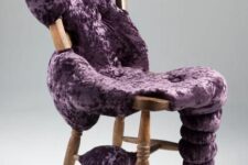a vintage stained chair with purple upholstery placed chaotically as if it’s slime flowing down to the floor