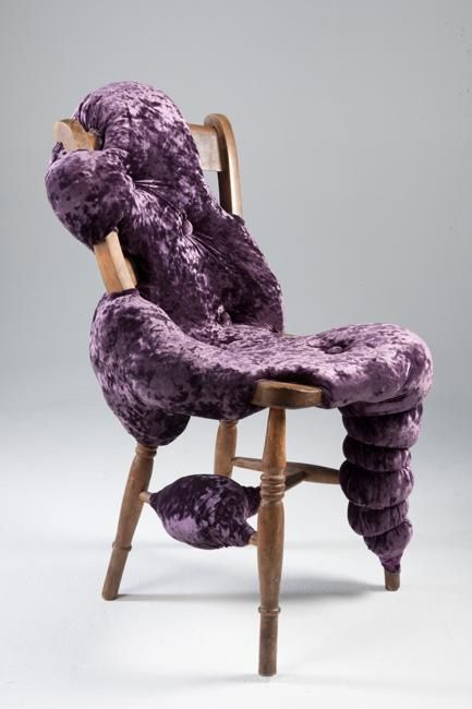 a vintage stained chair with purple upholstery placed chaotically as if it's slime flowing down to the floor