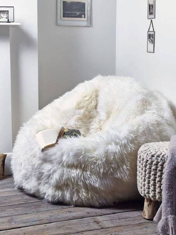 a white faux fur beanbag chair plus some cozy chunky knit stools are welcoming and cozy furniture for any space