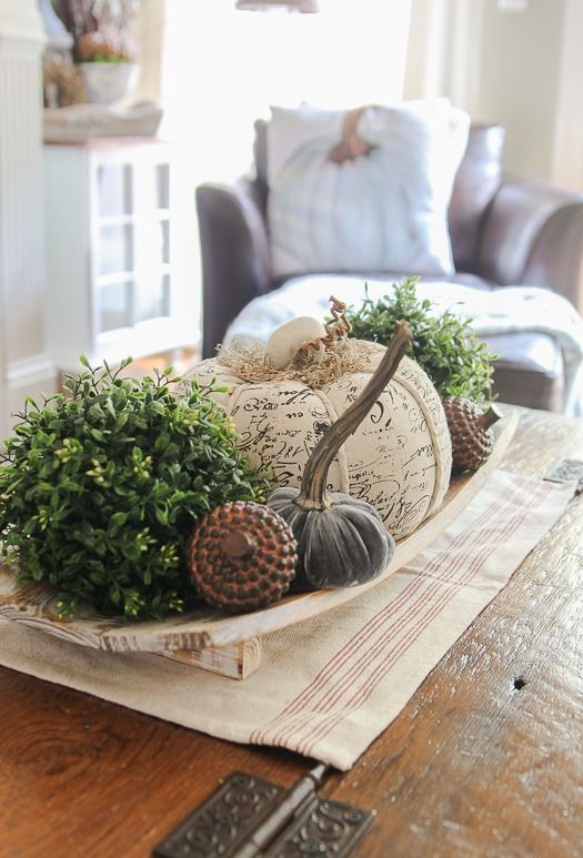 a wooden bowl with greenery balls, fabric pumpkins, fake acorns for a cool and bold famrhouse-inspired look