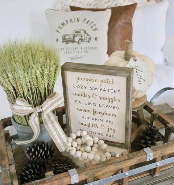 a wooden tray with beads, pinecones, wheat in a small bucket, fabric pumpkins and a sign for cozy fall decor