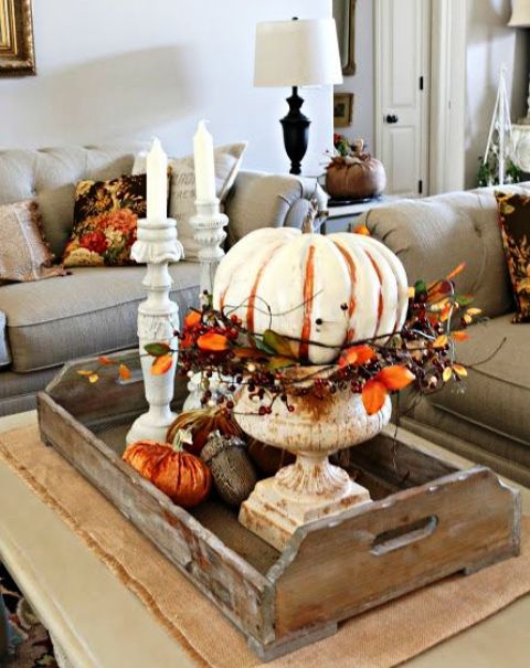 a wooden tray with orange fabric pumpkins, giant acorns and a large painted pumpkin with leaves and berries in an urn