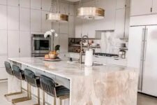 an elegant dove grey kitchen with a pink stone kitchen island, whimsy black and gold stools and gold pendant lamps