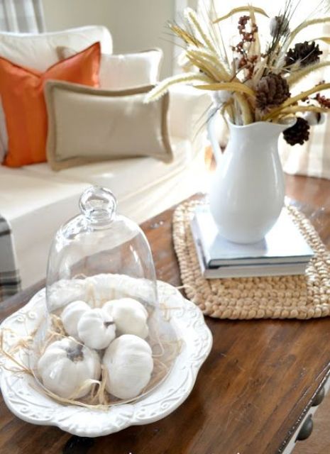 white pumpkins in a cloche and a white jug with dried blooms, leaves and wheat for cozy farmhouse living room decor