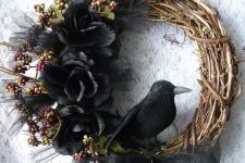 a Halloween rustic wreath of vine, with black blooms, berries and a crow is a refined and cool piece