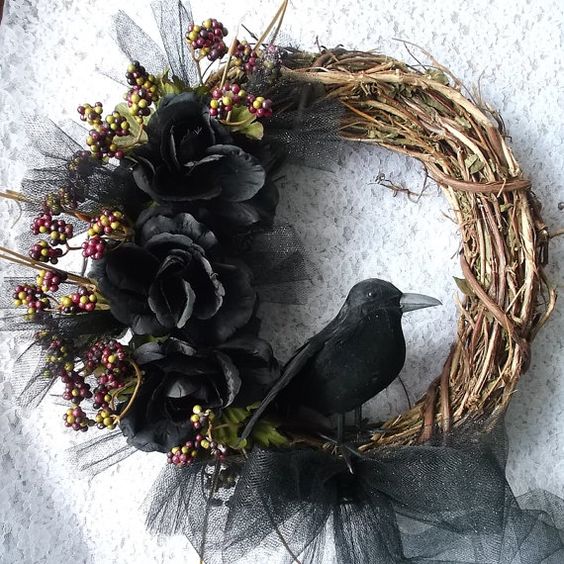 a Halloween rustic wreath of vine, with black blooms, berries and a crow is a refined and cool piece