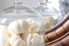 a Thanksgiving centerpiece of a cloche filled with white pumpkins and gourds, greenery is eays to make