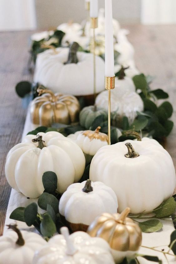 a beautiful Thanksgiving centerpiece of white, gilded and green pumpkins, gold candleholders with white candles