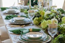a beautiful green Thanksgiving tablescape with green plates, napkins, flowers and greenery and some gold touches