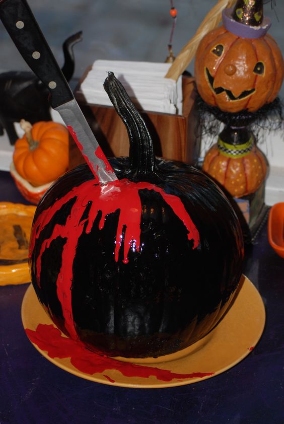 a black bloody pumpkin with a knife tucked in is a cool idea for Halloween party decor, whether it's a Dexter or some other one