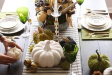 a bold Thanksgiving tablescape with a striped runner, green napkins and placemats, green glasses and faux pumpkins