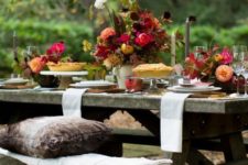 a bright and chic Thanksgiving table with bold florals, tall candles and some foliage plus neutral linens