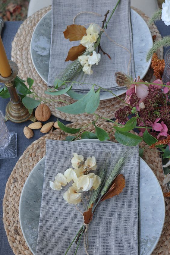 a bright vintage Thanksgiving tablescape with woven placemats, neutral linens, nuts, acorns, bright blooms and candles