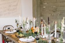 a chic Thanksgiving tablescape with woven placemats, tall candles, a greeneyr runner and some pumpkins