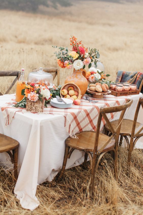 a chic and bright Thanksgiving table with bright florals, white pumpkins in cloches and a plaid tablecloth