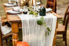 a chic natural Thanksgiving table with a runner, fresh pumpkins, tall candles and some leaves and vases