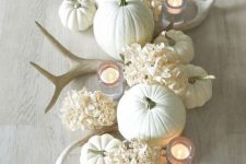 a chic white Thanksgiving centerpiece of white pumpkins, hydrangeas, antlers and candles is beautiful