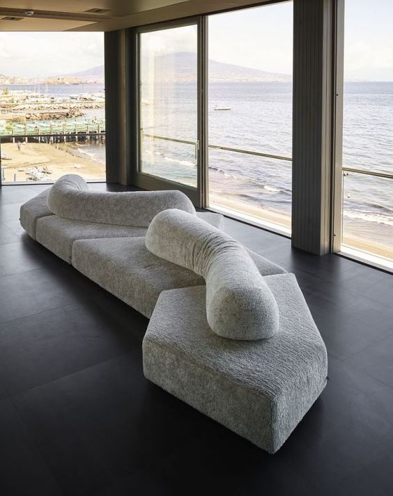 a creative sculptural sofa in grey, composed of some pieces and some cushions on top is a lovely piece inspired by the rocks