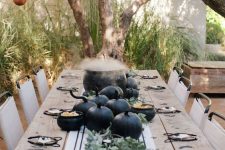 a farmhouse Halloween tablescape with black pumpkins, greenery and a cauldron as a centerpiece