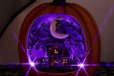 a faux pumpkin with a purple Halloween scene inside – a house with scary trees and a crescent moon with a witch