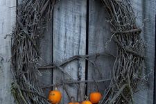 a grapevine wreath with little orange pumpkins is all you need to craft for your front door at Halloween