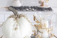 a refined Thanksgiving centerpiece of a mirror and gold tray, white embellished fabric pumpkins and a candle ina glass candleholder