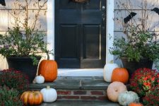 a rustic Halloween porch with natural pumpkins, a vine wreath with bats and branches with bats