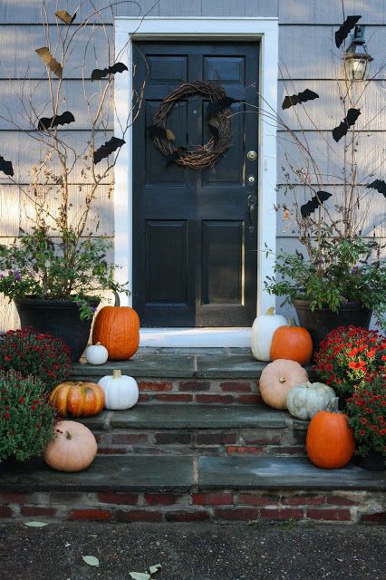 a rustic Halloween porch with natural pumpkins, a vine wreath with bats and branches with bats