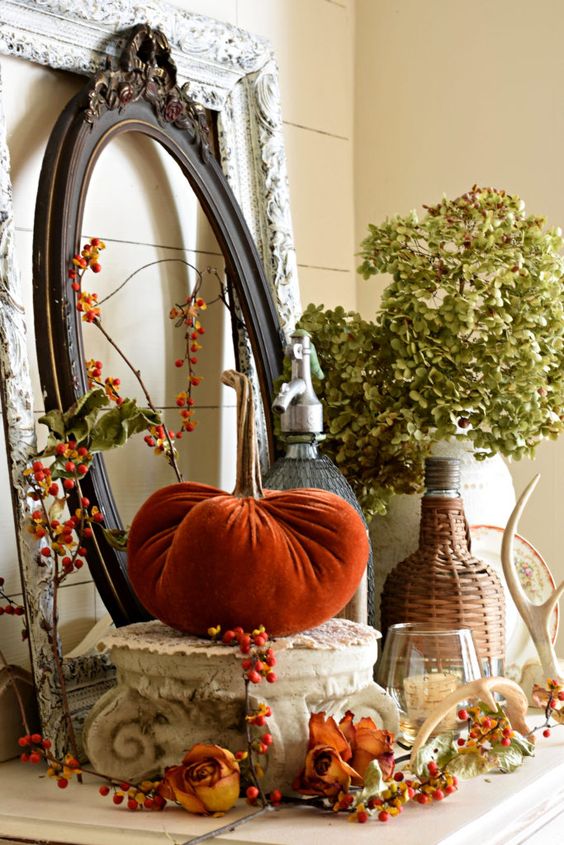 a rustic vintage Thanksgiving mantel with dried blooms, berries, leaves, antlers and vintage picture frames