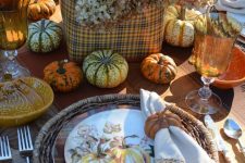 a rustic vintage Thanksgiving table with woven chargers, printed plates, natural pumpkins, a plaid box with hydrangeas