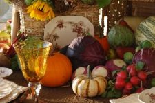a rustic vintage Thanksgiving tablescape with plaid napkins, a veggie, greenery and bright sunflower centerpiece, colorful glasses