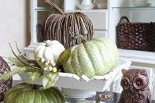 a rustic vintage centerpiece of white, green and vine pumpkins, berries and an owl is ideal for Thanksgiving
