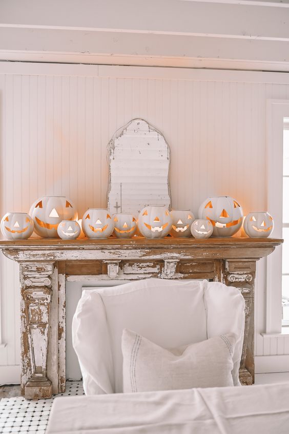 a shabby chic mantel styled with a lot of white jack-o-lanterns is a gorgeous and non-traditional idea for Halloween