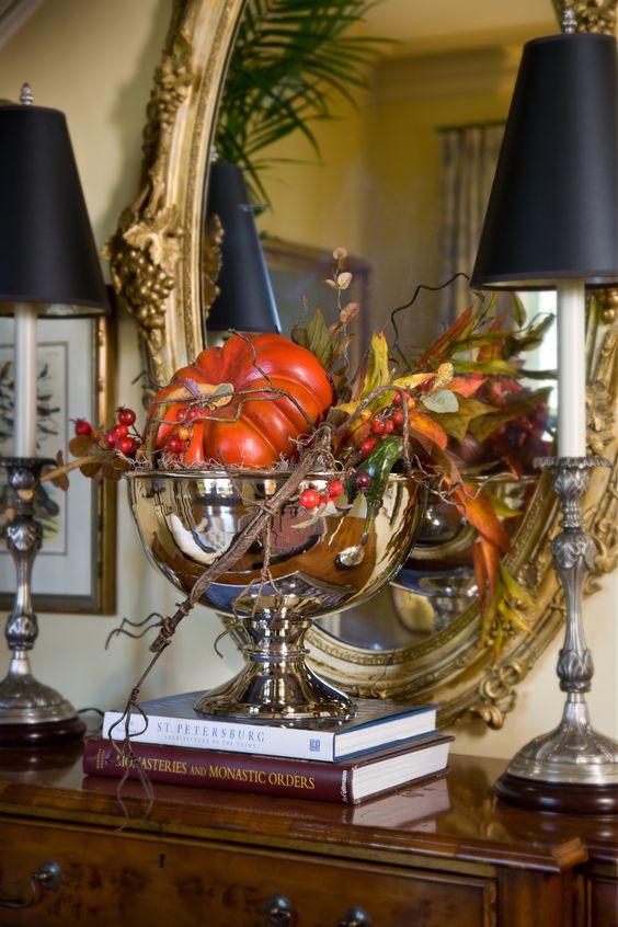 a shiny metallic bowl with faux pumpkins, greenery, berries and twigs for Thanksgiving decor