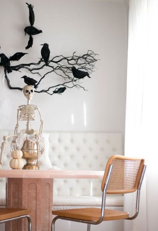 a skeleton on a metallic jar, with a stack of pumpkins, black branches with blackbirds are amazing for Halloween decor