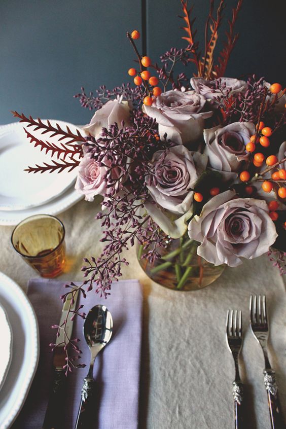 a sophisticated Thanksgiving tablescape with lilac napkins and a neutral tablecloth, lilac blooms, berries and vintage cutlery
