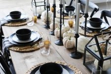 a stylish rustic Halloween tablescape with woven placemats, black plates and candleholders, white pumpkins and gold glasses