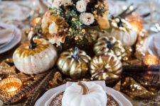 a vintage boho Thanksgiving tablescape with printed linens and plates, gold chargers, cutlery, pumpkins and candleholders, feathers and blush blooms